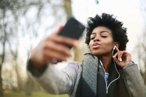 A young black female listening to the music with white headphones