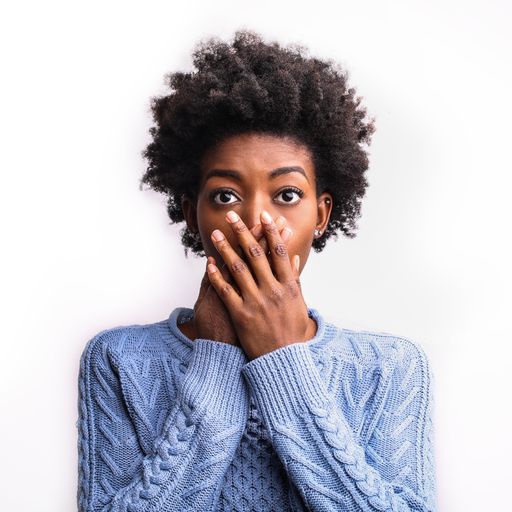 A vertical portrait of a surprised black female with a blue shirt isolated on a white background