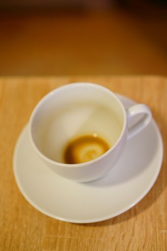 A vertical shot of an empty white mug on a wooden surface