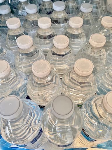 A vertical shot of filled water bottles with caps