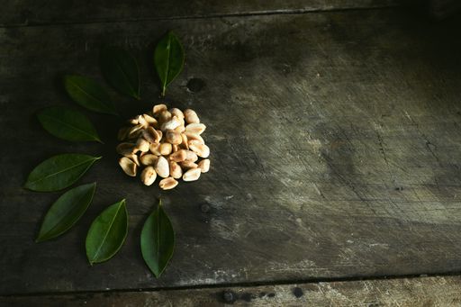 A high angle view of pistachios with green artificial leaves on a wooden table