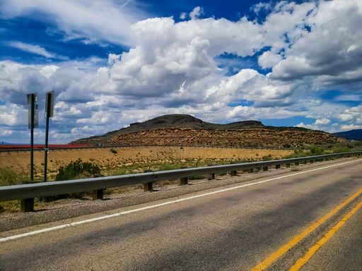 A road surrounded by hills under a blue cloudy sky in the countryside
