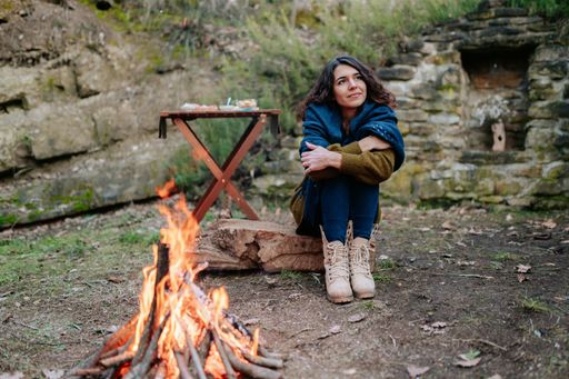 A young woman sitting next to a fire during a winter picnic and enjoying the view
