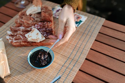 A top view of a female hand serving jam on a table set with appetizers and tasty food