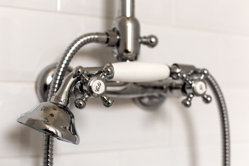 A shallow focus of a bathtub spout in a bathroom with a blurred white wall in the background