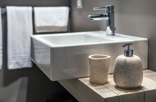 A shallow shot of a modern sink beside the bottle in the bathroom