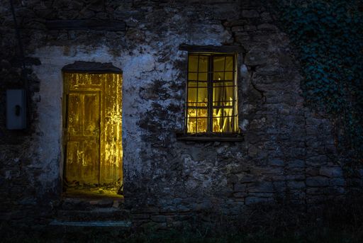 A landscape shot of a gray wall with an open window with yellow light color inside of an open space room