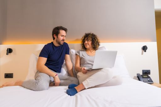 A closeup shot of a cute couple lying on a bed and watching a film on a laptop