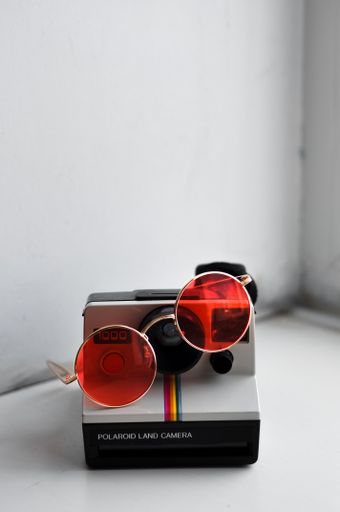 Retro polaroid camera with glasses on white background