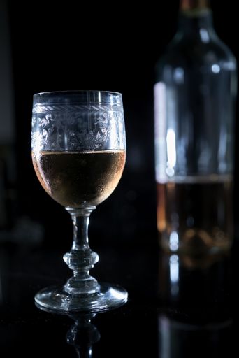 A vertical closeup shot of a glass of wine on a table with a blurred background
