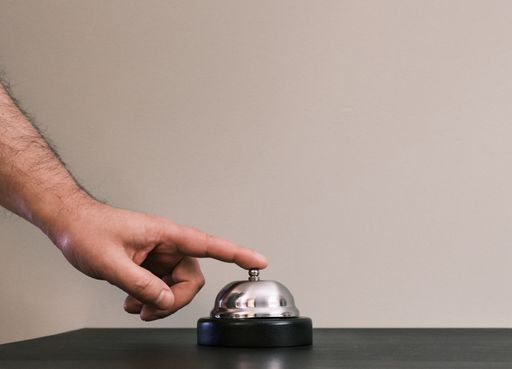 The hand of a person pressing the bell at the reception