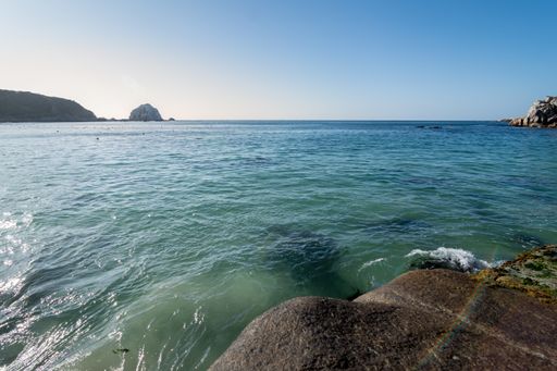 A beautiful view of a sea with splashing waves and rock formations on the beach under the sunlight