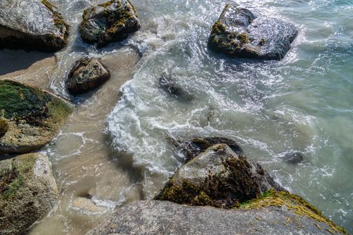 A beautiful view of a sea with splashing waves and rock formations on the beach under the sunlight