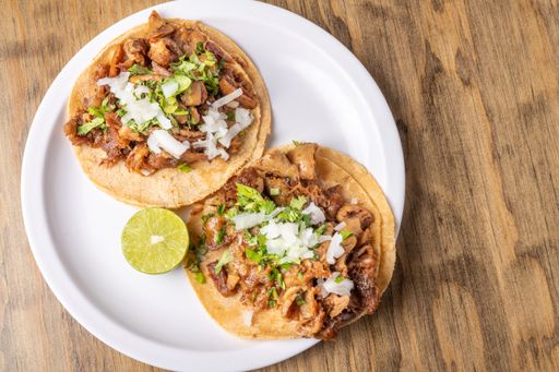 A top view of delicious traditional Mexican tacos and lime on a plate on a table