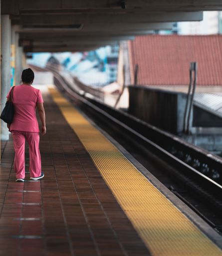 A female in a pink uniform waiting for the train in a station