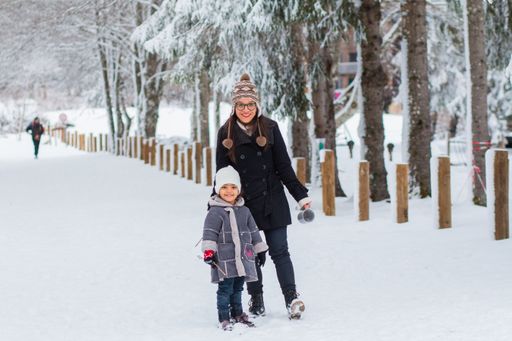 A Caucasian mother and her daughter wearing winter clothes walking in a park on a winter day