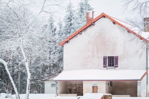 A beautiful view of a house surrounded by trees covered in snow on a cold winter day