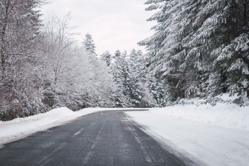 A beautiful winter landscape with a road surrounded by trees covered in snow