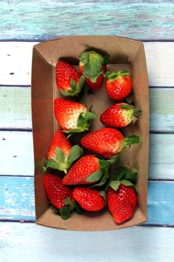A vertical closeup shot of fresh strawberries in a paper plate