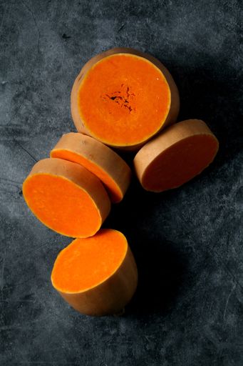 A vertical top view of sliced butternut squash isolated on a dark-gray ceramic surface