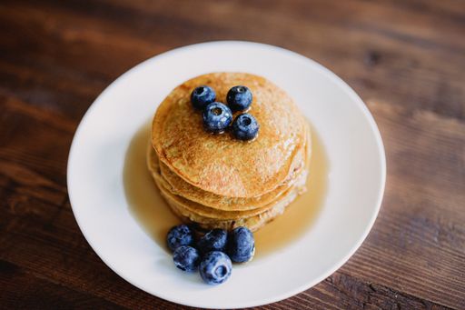A closeup shot of delicious and appetizing pancakes with blueberries on a white plate