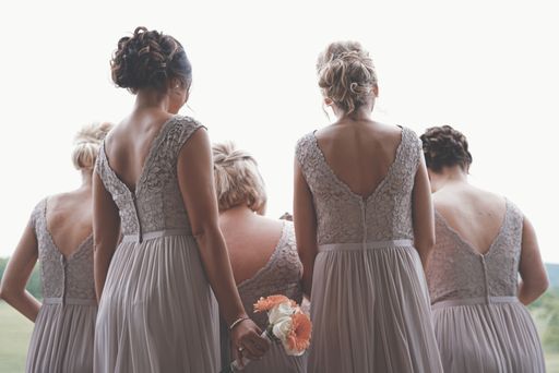 A behind shot of beautiful bridesmaids wearing cream-colored dresses at a wedding