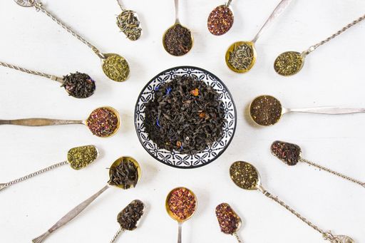 A top view of a set of dry tea assortment on vintage silverware spoons arranged in a circle