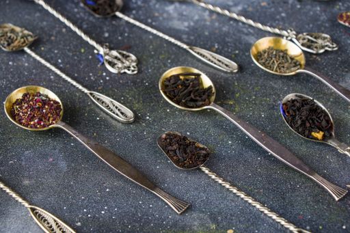 A set of dry tea assortment on vintage silverware spoons neatly arranged on a table surface