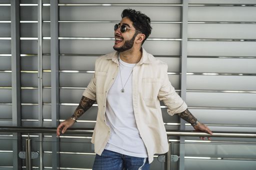 A shallow focus shot of a handsome European male with tattoos and in sunglasses posing at camera