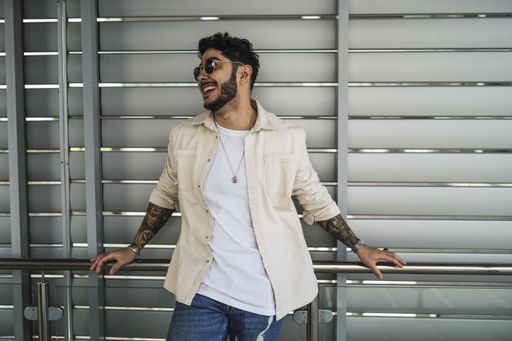 A shallow focus shot of a handsome European male with tattoos and in sunglasses posing at camera