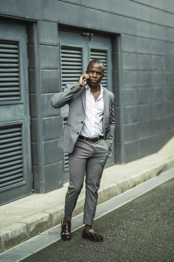 A vertical shot of a handsome confident African male in a suit talking on the phone