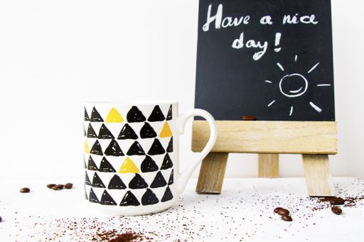 A selective focus shot of a cup of tea and a wooden blackboard with the text "Have a nice day" on a table