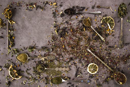 An assortment of dry tea on vintage silverware spoons, black, flower, green, and mint tea