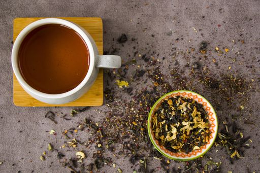 A flat lay composition with a cup of black tea and vintage silverware spoons with an assortment of dry tea leaves