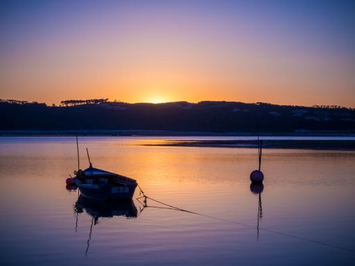 An old fishing boat at the river with the breathtaking view of the sunset in the background