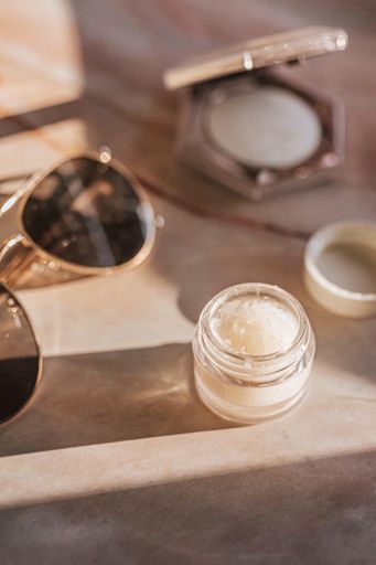 A selective focus of a small container with cream next to sunglasses on the table