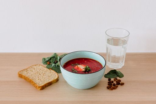 A closeup shot of borscht and bread with a glass of water