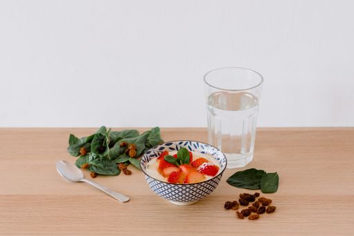 A closeup shot of a bowl with strawberries and milk with a glass of water