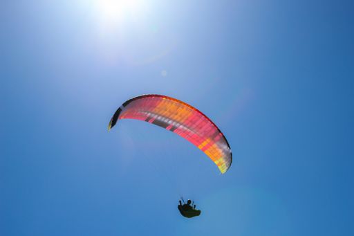A low angle shot of a person paragliding on a sunny day under the bright sky