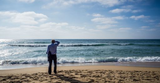 A lonely person in a formal outfit walking on the beach enjoying the beautiful view of the sea