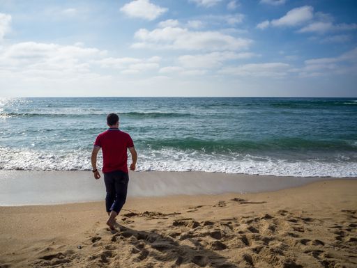 A lonely male walking on the beach under the beautiful cloudy sky