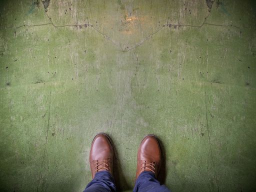 A high angle shot of a person with brown shoes on a weathered green surface