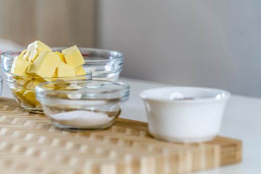A closeup of kitchen equipment with flour, cocoa powder, eggs, and butter for baking a cake