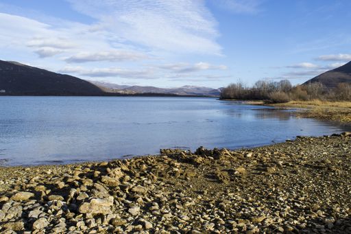 A beautiful panoramic shot of a stony serene shore under a blue cloudy sky