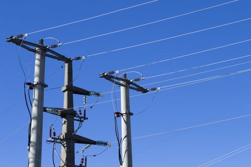 closeup shot of electric posts and lines against a blue background