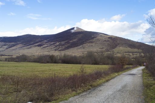 A panoramic shot of a mountain and valley with a road on the side on a bright day