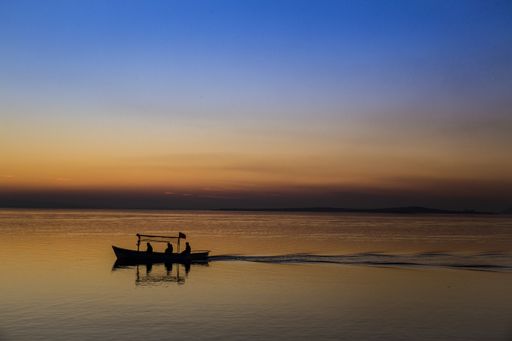 A silhouette of fishermen on boat at sunset