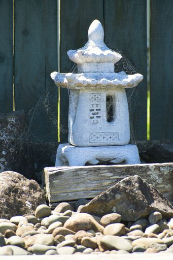 A vertical sho of an old Japanese stone lantern displayed outdoors