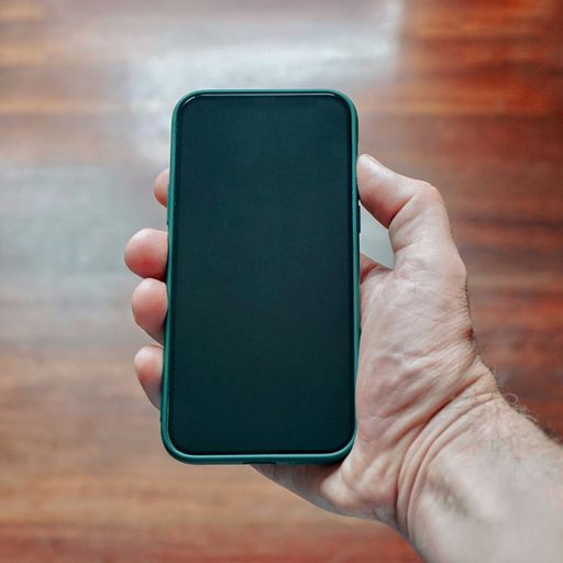 A closeup of a hand holding a smartphone with black screen on blurred wooden background