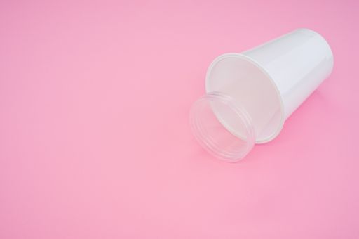 A high angle shot of big and small plastic cups on a pink surface